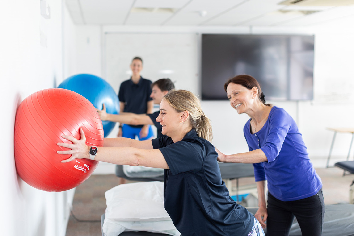 A woman with an exercise ball pressed against the wall.