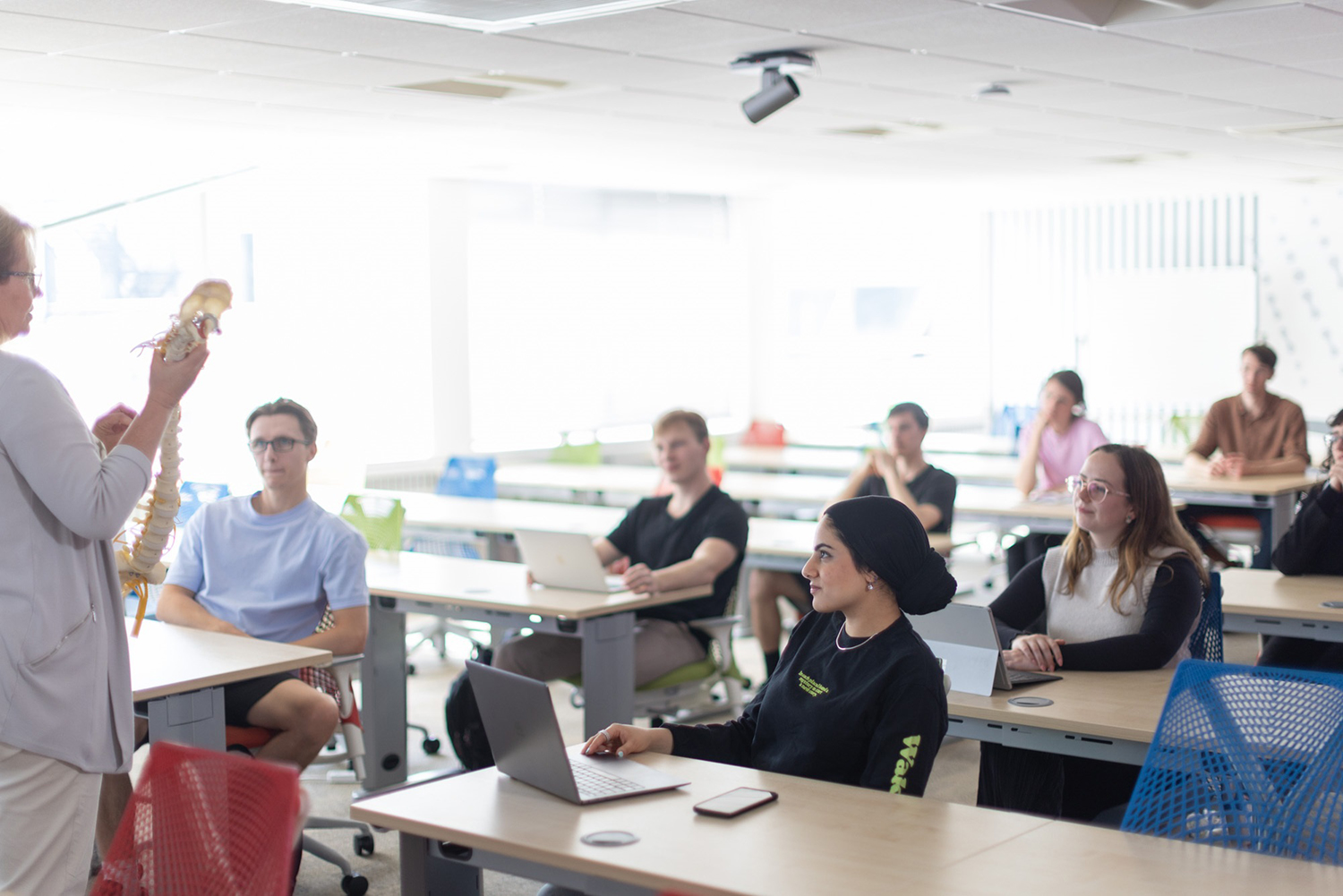 Students sit listening to a teacher in the classroom