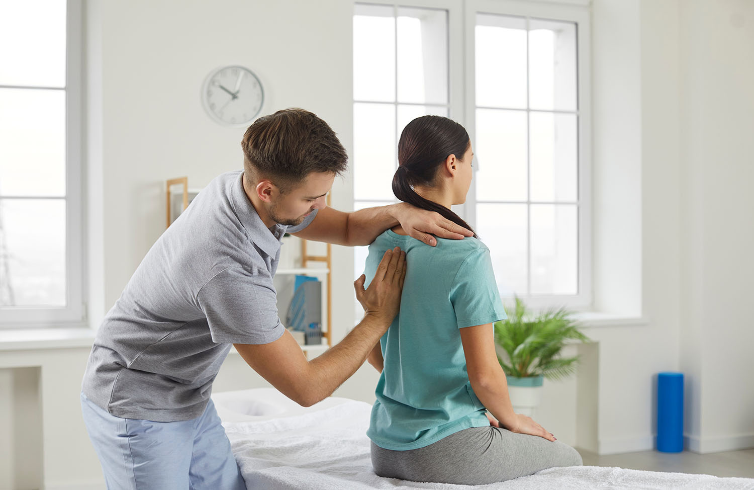 Male chiropractor, physiotherapist or osteopathy specialist examining a female patient.