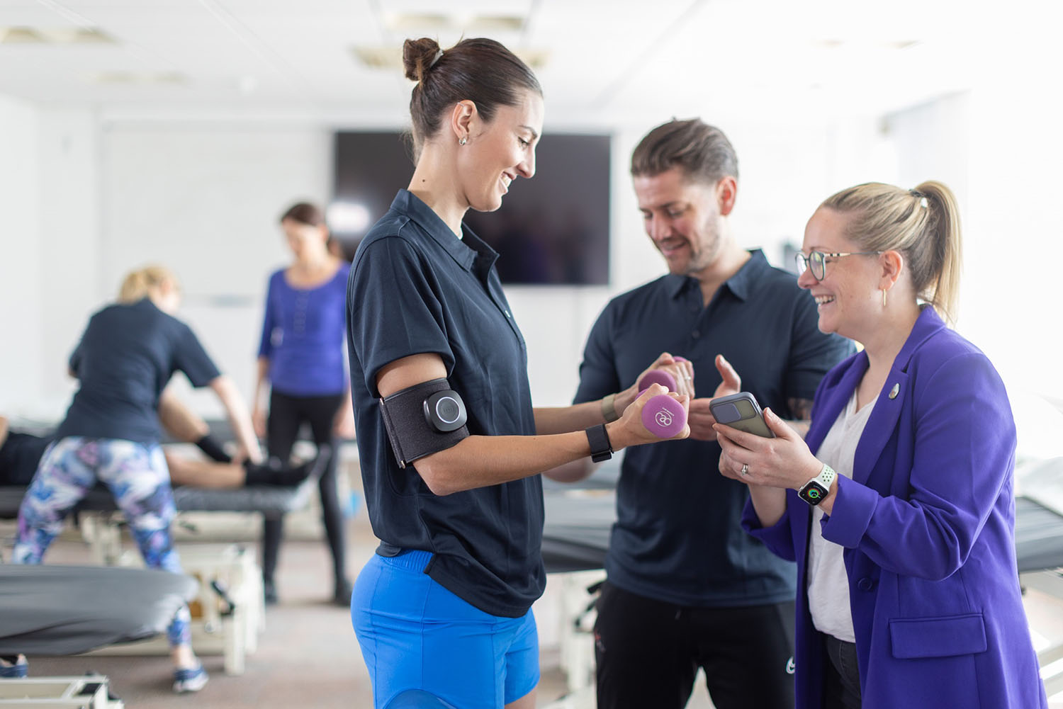A woman is coached while lifting weights.