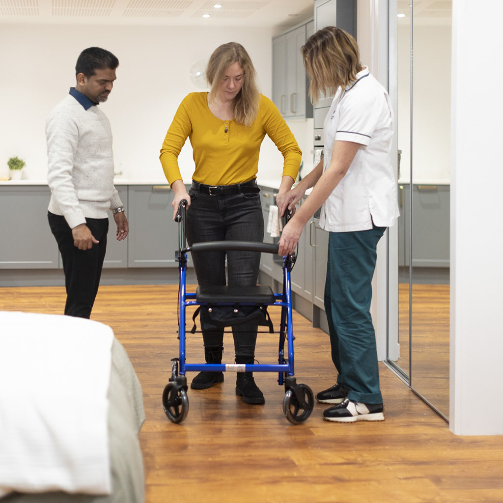 People demonstrating with a walker in the assisted daily living suite.