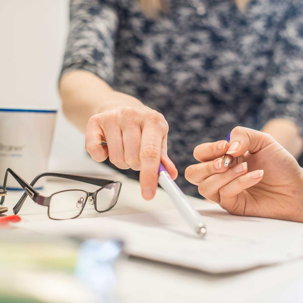 Somebody points to a notepad on a table. 