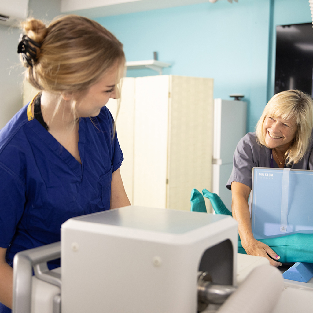 A woman smiles as she operates a machine.
