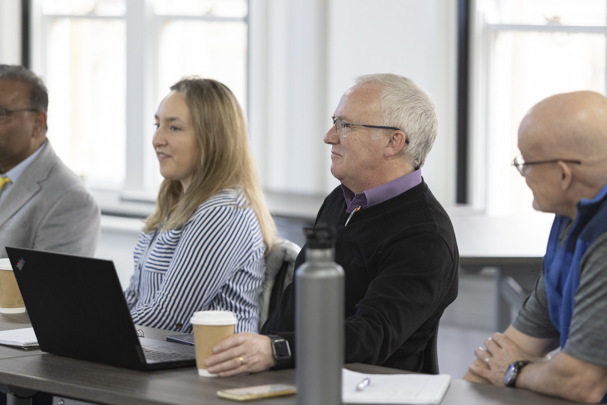 a group with laptops listen to a speaker.