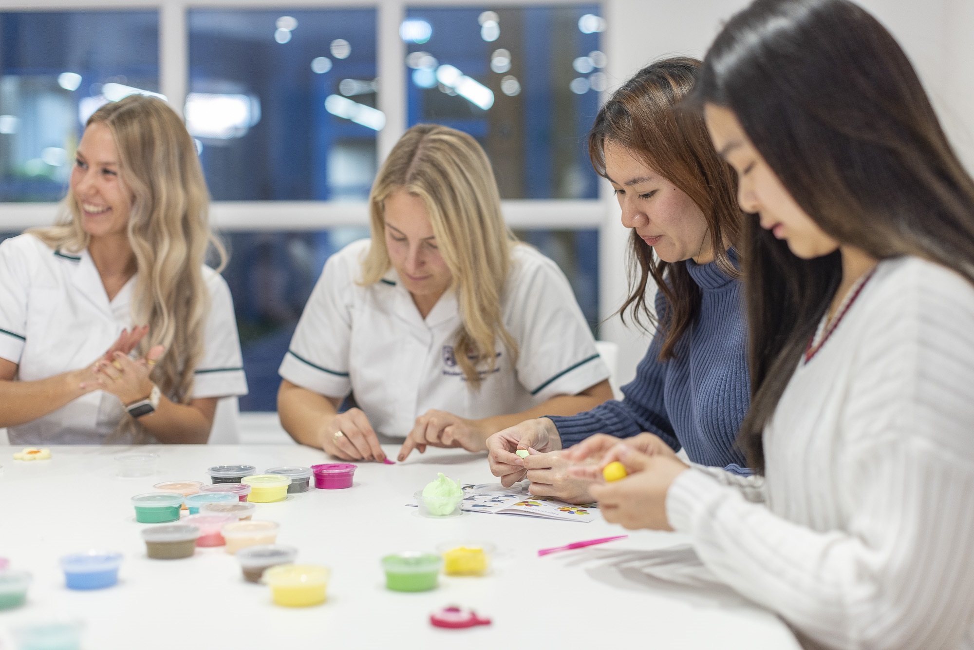 OT students gathered around a table doing an excercise with playdough like objects.