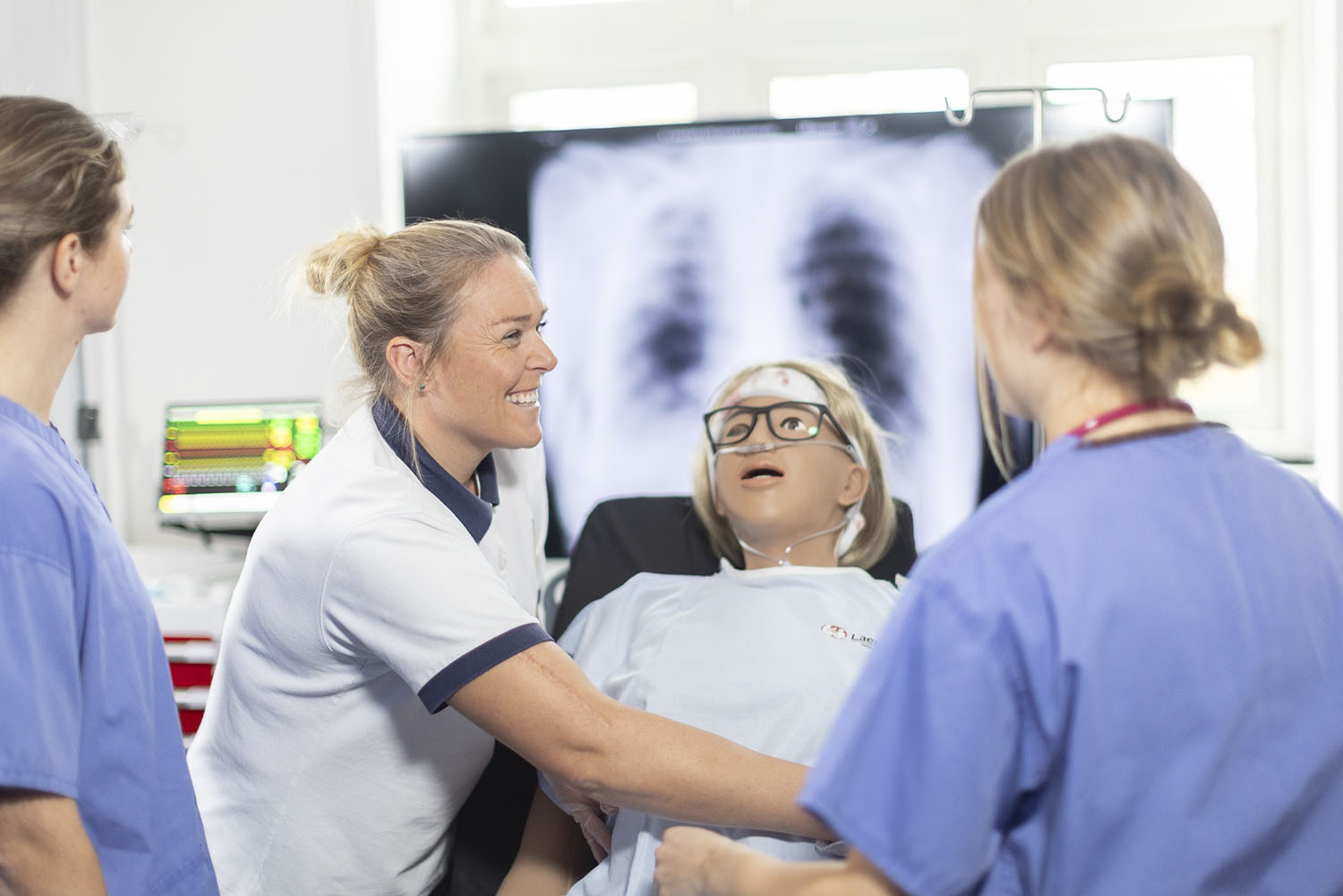 a physio smiles as she does a demonstration with students.